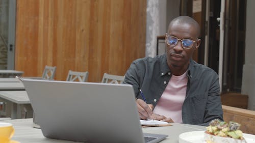 Man Writing on the Table While Having a Meal