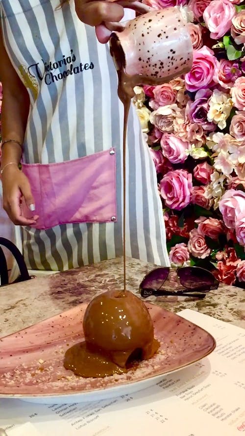 Person Pouring Chocolate on a Dessert