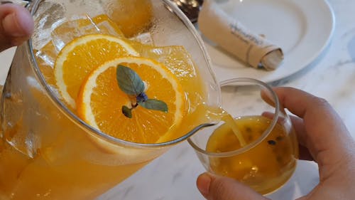 Person Pouring an Orange Juice