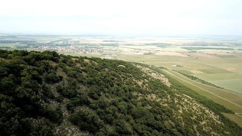 Aerial View of Paraglider over a Green Mountain