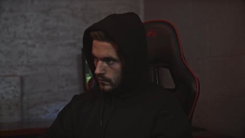 Man in Black Hoodie Looking Pensive at the Computer