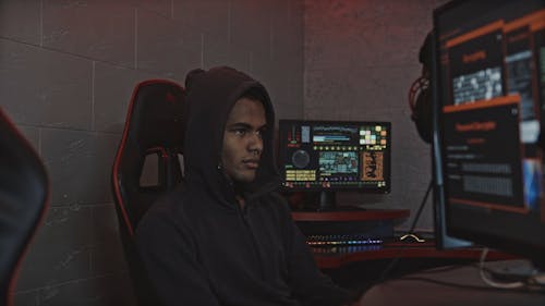 Man in Black Hoodie Looking Pensive While Sitting on a Gaming Chair
