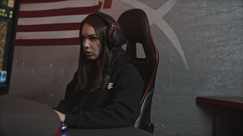 Woman in Black Hoodie Sitting on a Gaming Chair While Using Her Computer