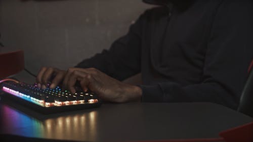 A Person Typing while Wearing a Hacker Mask