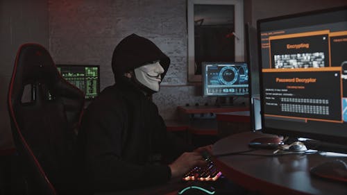 A Person Typing on Keyboard while Wearing a Hacker Mask