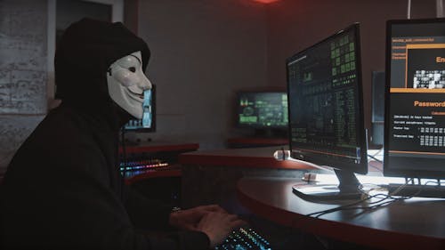 A Person Wearing a Guy Fawkes Mask While Using His Computer