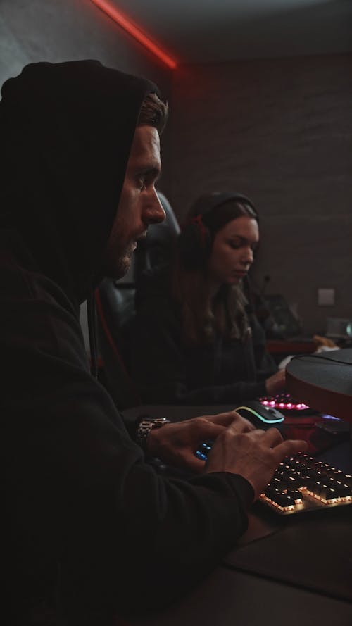 Man and Woman Typing on a Mechanical Keyboard While Looking Determined