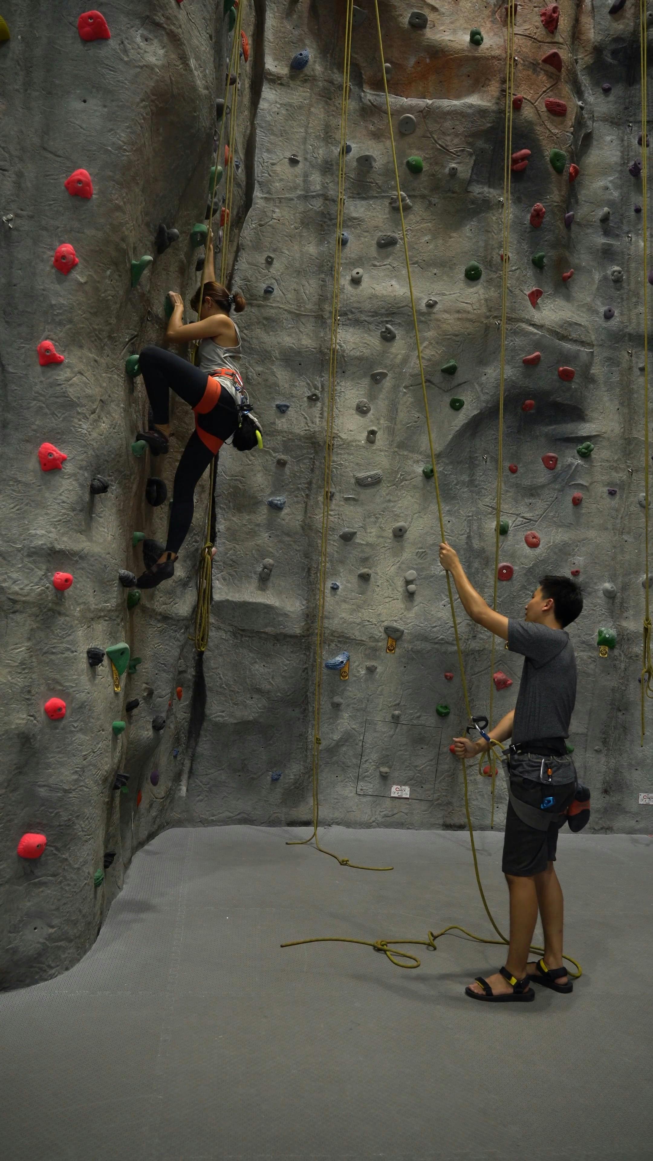 A Woman Climbing Up the Wall While a Man Standing on the Ground · Free