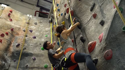 Low Angle Shot of a Man and Woman Climbing Up the Wall