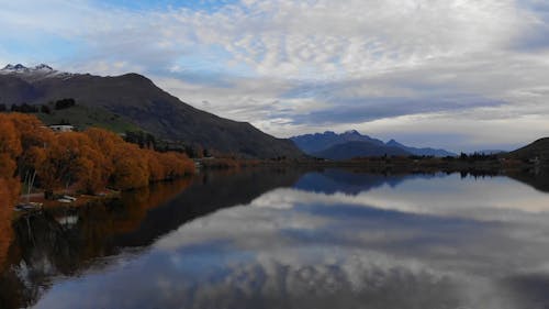 Beautiful Scenery of a Calm Lake Across the Mountains Under Cloudy Sky