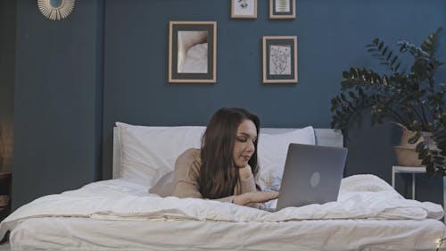 A Woman Using A Laptop In Bed