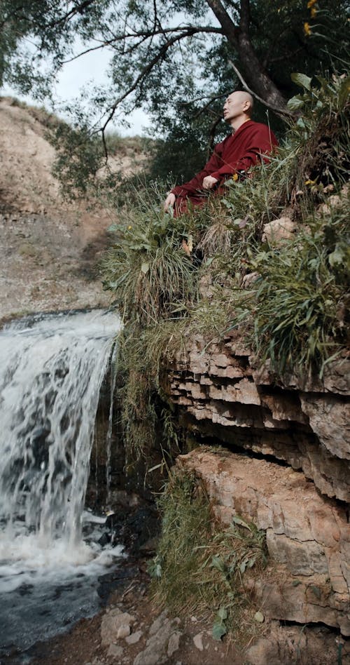 A Monk Meditating Near A Waterfall