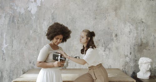 Two Women Holding Different Cameras
