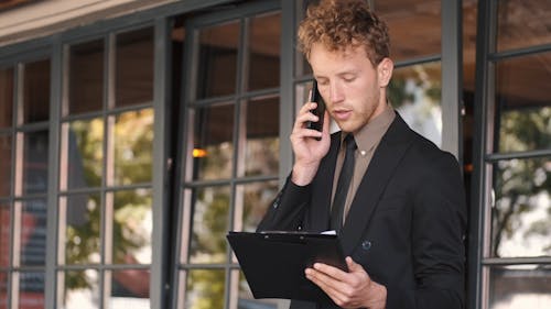 Young Businessman Reading Papers and Talking on Phone