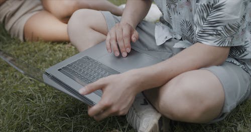 Man Sitting On A Grassfield Using A Laptop