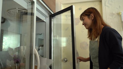 A Woman Getting a Bouquet of Flowers from the Fridge