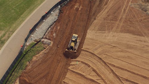 A Bulldozer Leveling the Soil in the Construction Site