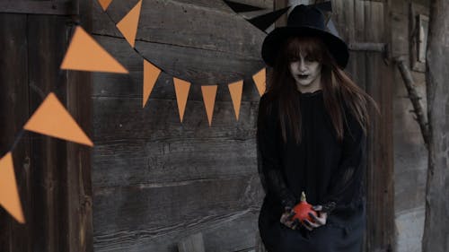 Witch Standing in Front of a Cabin