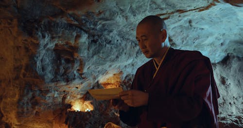 A Monk Reading Buddhist Text Inside a Cave