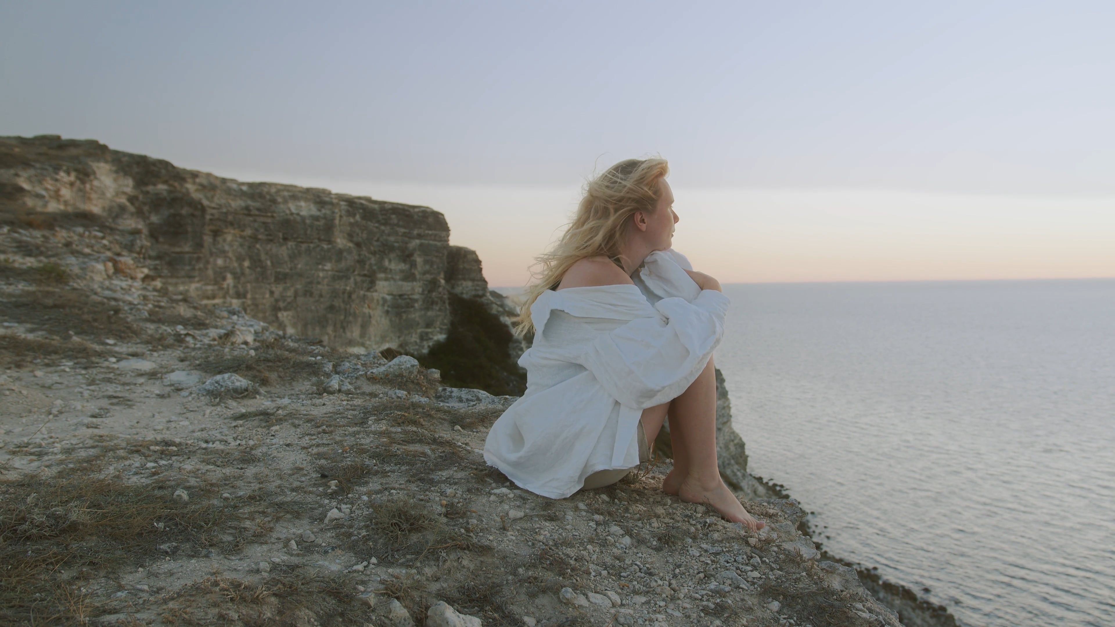 A Woman Sitting on a Cliff Looking at the Ocean Free Stock Video ...