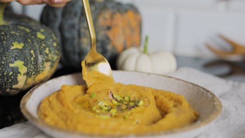 A Person Scooping Pumpkin Soup Using a Spoon