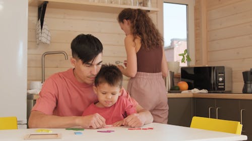 Father Playing with His Son While Mother Prepares Food