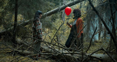 Clown Giving Balloon to a Young Girl in the Forest