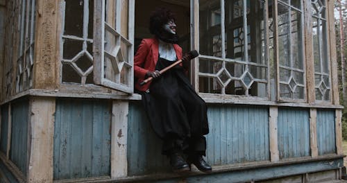 Creepy Smiling Clown Sitting on Abandoned House Window