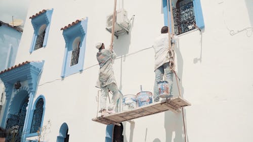 Worker Painting the Building in Blue Color