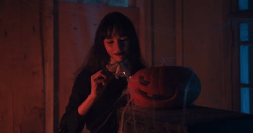 Woman Lighting a Pumpkin Lamp