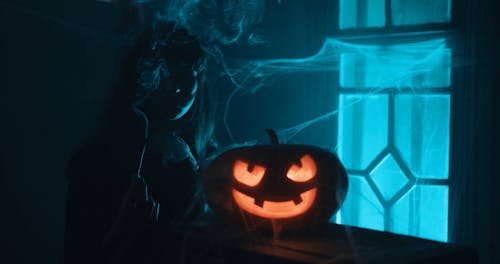 Young Woman with Glowing Halloween Pumpkin 