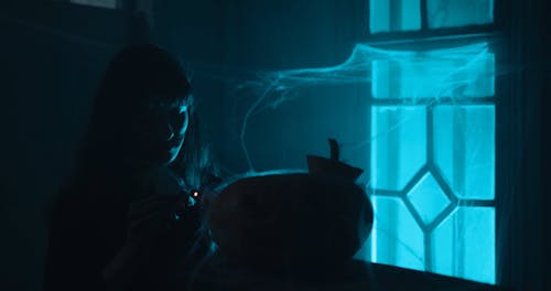 Woman Lighting a Pumpkin Lantern