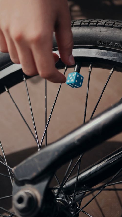 Person Unscrewing a Valve Cap on a Bicycle Wheel