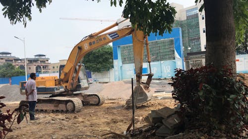 Person Operating a Backhoe on the Construction Site