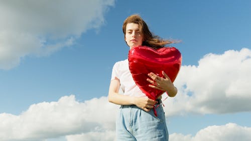 Woman Holding a Heart Shaped Balloon on the Outdoors