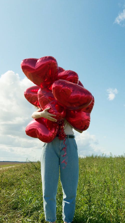 Woman Holding a Heart Shaped Balloons on the Outdoors