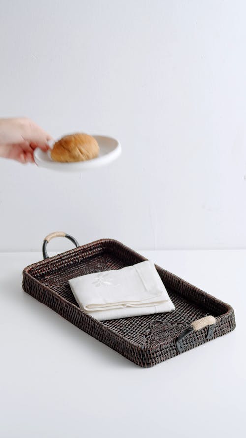Person Putting a Plate with Bread on the Tray