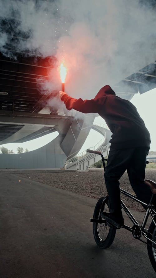 Person Holding a Flare while Riding a BMX