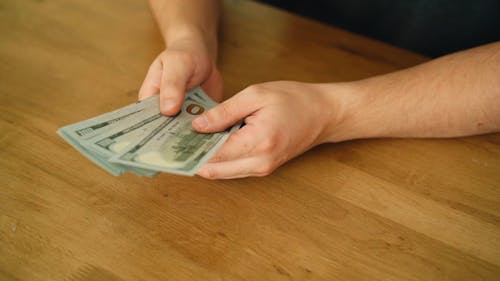 A Person Holding Hundred Dollar Bills on Both Hands