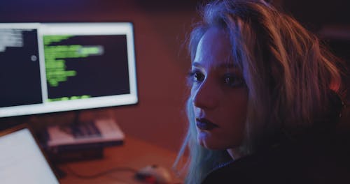 A Beautiful Woman Checking Code from One Monitor to Other