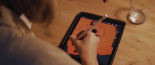 A Person Designing a Halloween Themed Poster on a Tablet