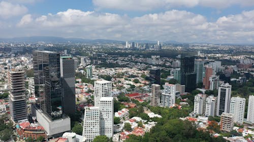 Drone Footage of City Buildings Under White Clouds