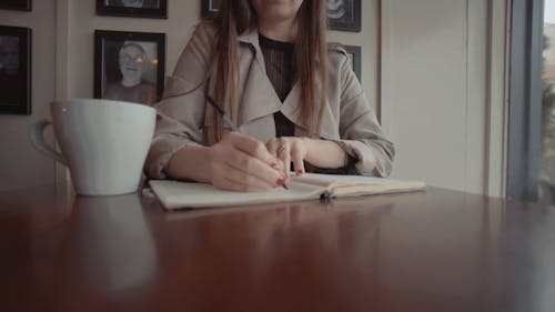 A Person Writing on a Notebook