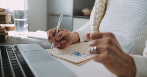 An Elderly Woman Drawing Sketches And Writing Notes