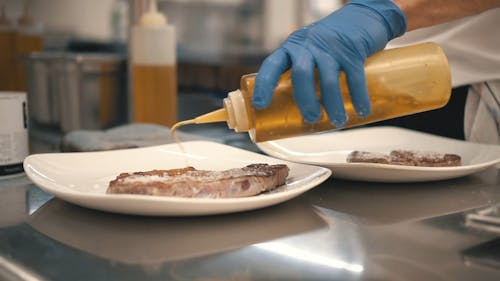 Person Pouring a Sauce on the Freshly Cooked Food