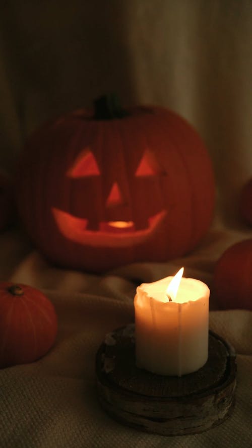 A Lighted Candle Blown Out Near a Carved Pumpkin