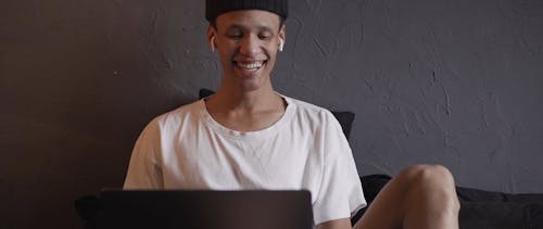 A Man Smiling While Using His Laptop