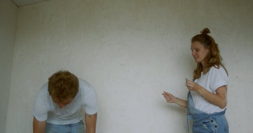 A Couple Working In Tandem In Painting Their Home