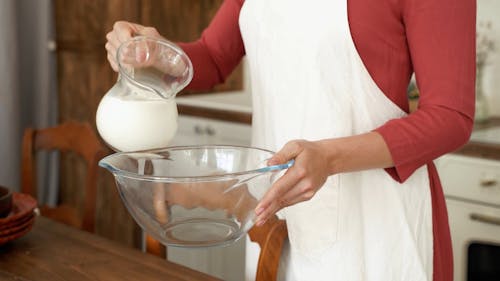 Female Hands Pouring Milk in Glass Bowl