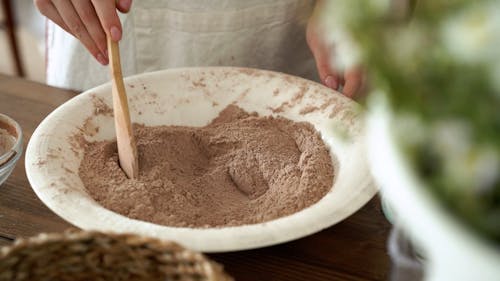Female Hands Mixing Chocolate Powder with Wooden Spoon